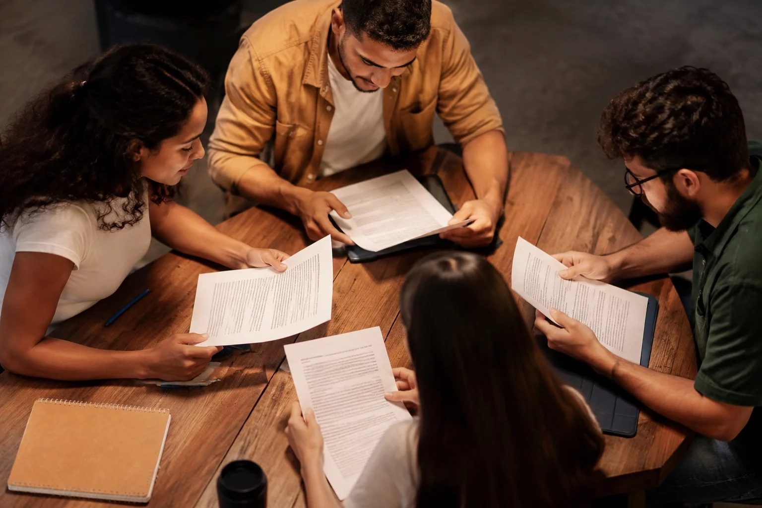 Grupo pequeno lendo páginas impressas de argumentos ao redor de uma mesa